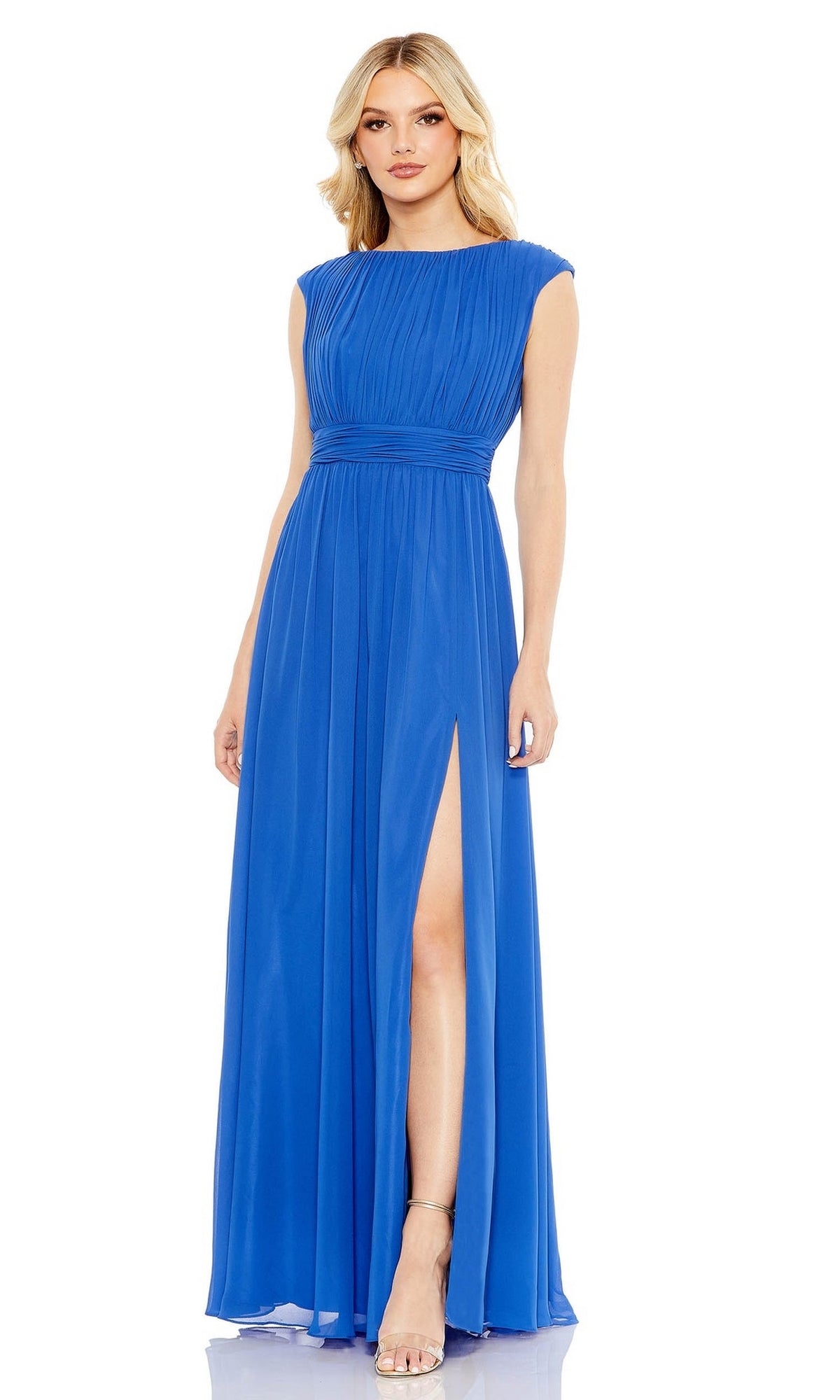 A woman wears the Long Formal Dress 55863 by Mac Duggal, a cobalt blue gown with a pleated bodice and high slit, styled with nude heels.